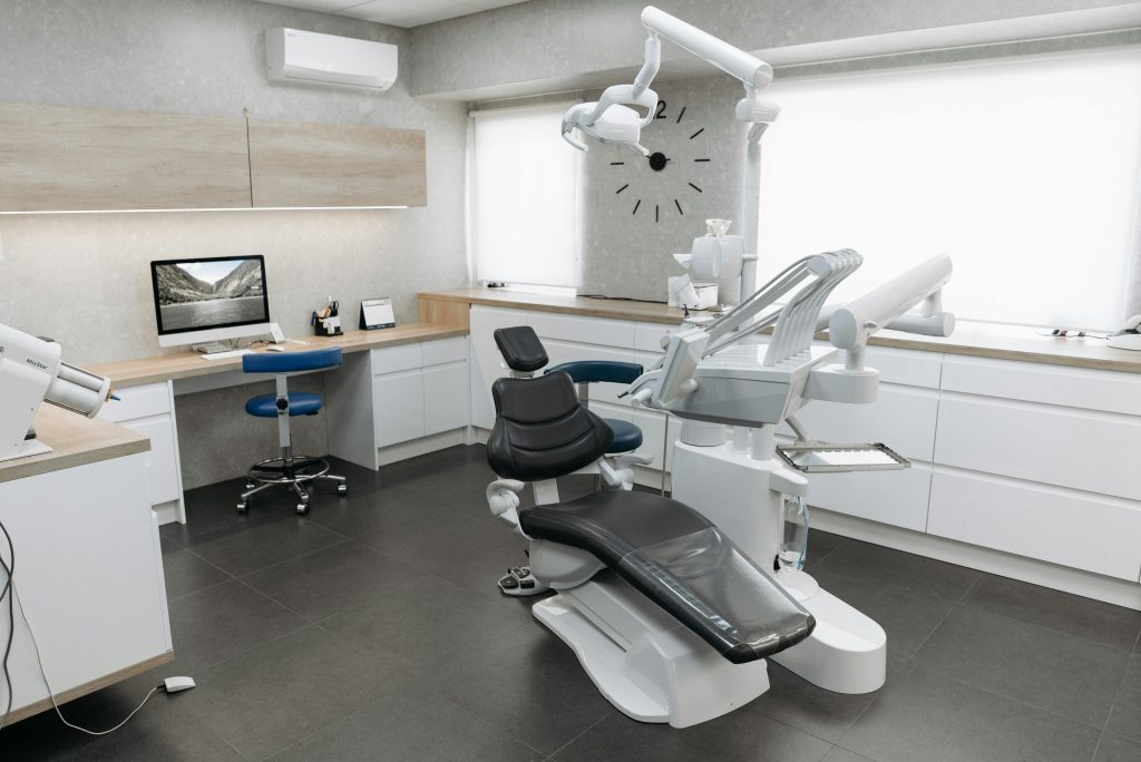 A modern dental clinic interior featuring a dental chair and equipment with a minimalist design.